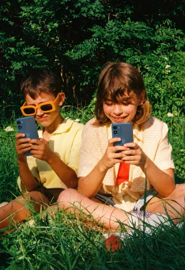 Two kids using a phone outdoors